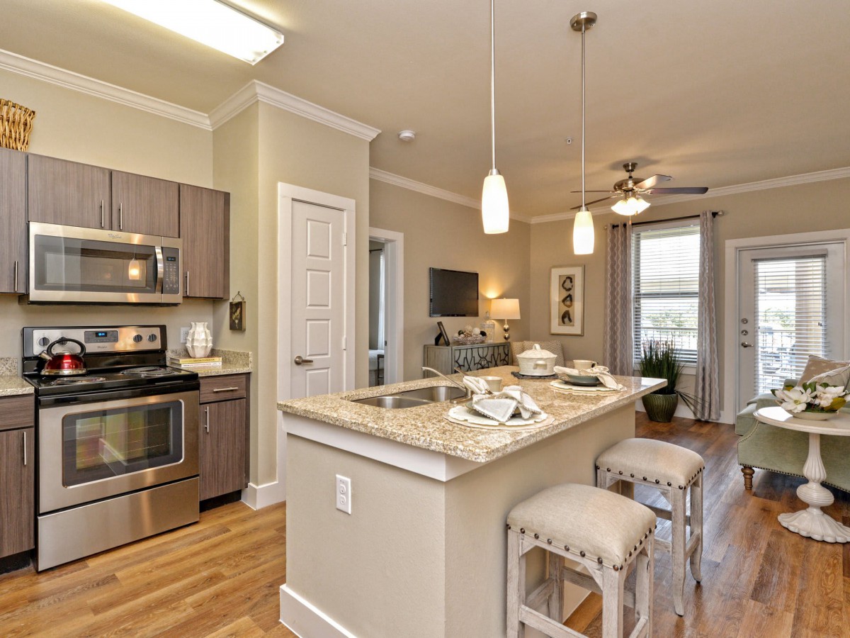 A modern kitchen features stainless steel appliances and an island counter with bar stools, creating an open and inviting space.
