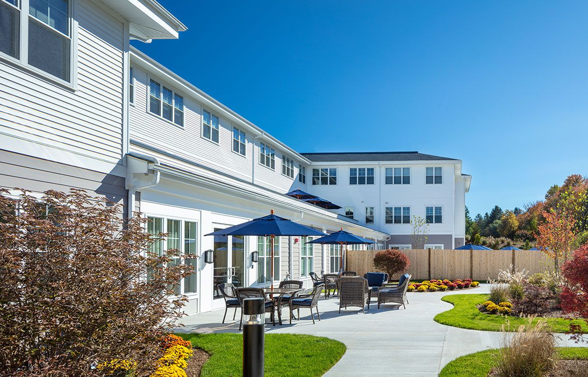 A modern building with outdoor patio seating and umbrellas on a sunny day.