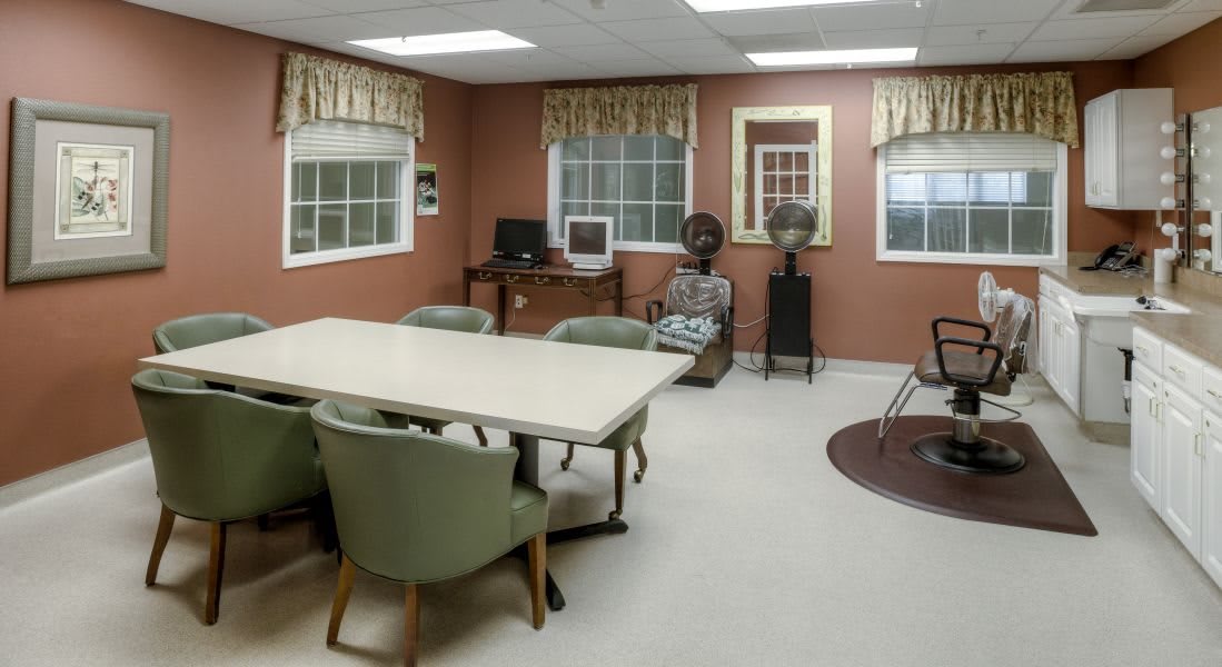 A spacious conference room with a table and chairs, featuring a computer desk and large windows.