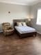 A cozy bedroom with a bed and armchair on a wooden floor.