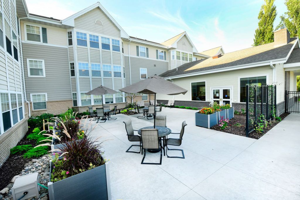 A sunny outdoor patio area with tables and chairs next to a modern building.