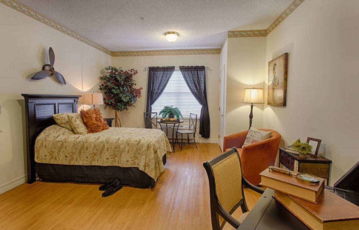 A cozy bedroom interior with stylish decor featuring a comfortable bed, seating area, and natural lighting from a window.