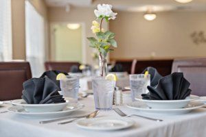 An elegantly set dining table with a flower centerpiece and neatly folded black napkins.
