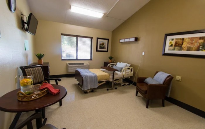 A hospital room with a single bed and seating area.