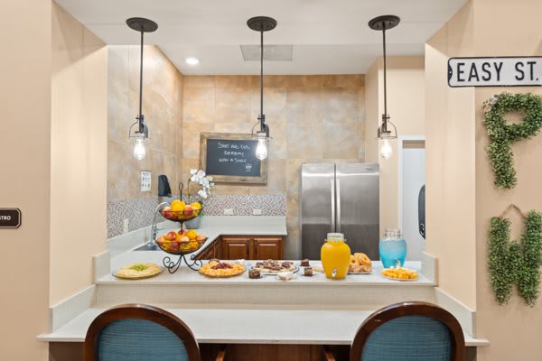 A modern kitchen with a breakfast bar, featuring pendant lights and stainless steel appliances.