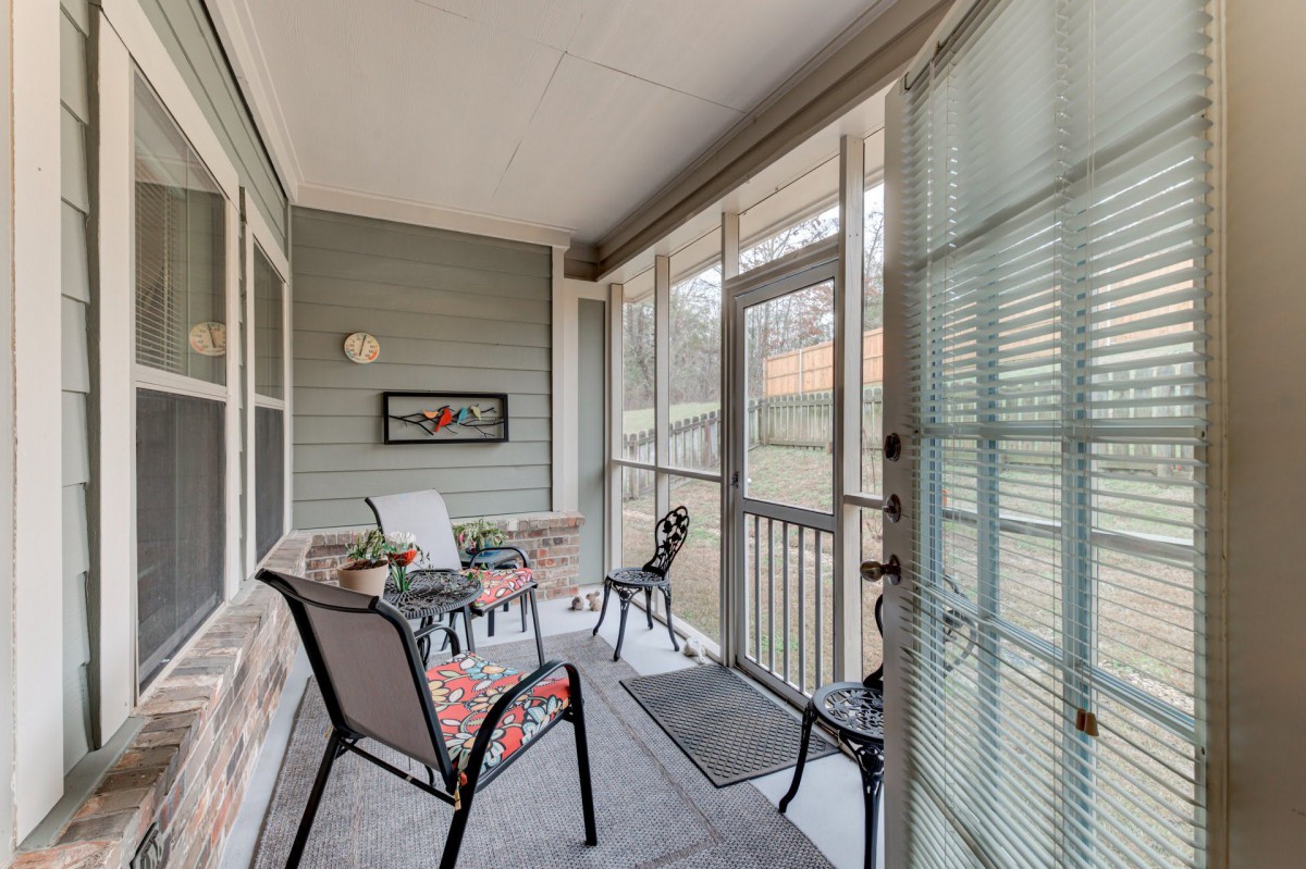 A cozy screened porch featuring a small table and several chairs, ideal for relaxing outdoors.