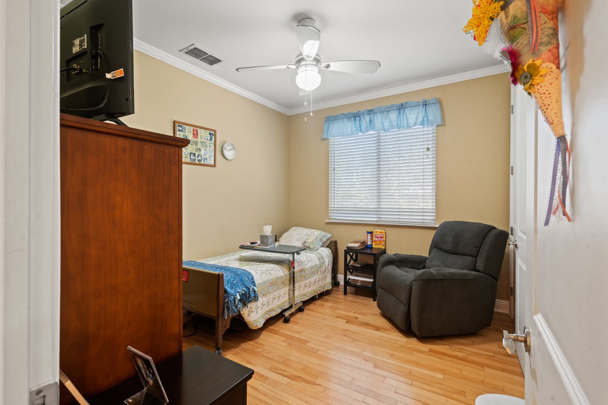 A cozy bedroom with a single bed, armchair, and wooden flooring.
