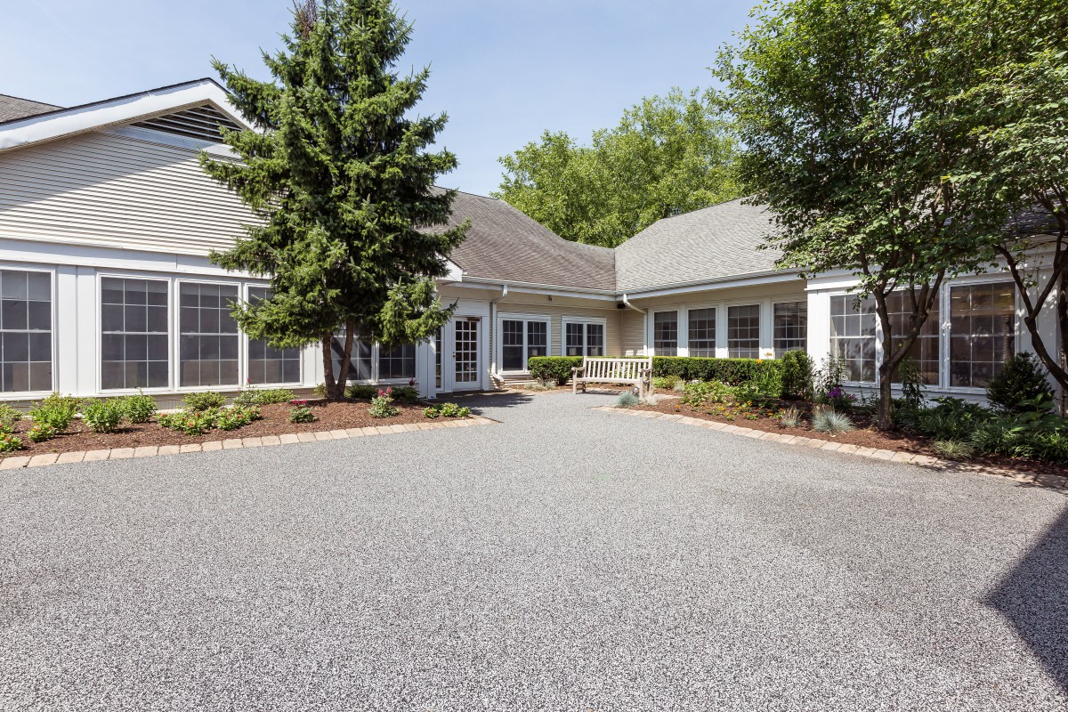 A spacious suburban house with a gravel driveway and surrounding greenery.
