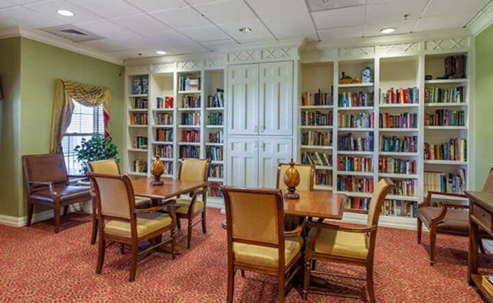 A cozy library with bookshelves, tables, and chairs providing a comfortable reading area.