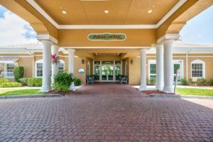 The entrance of a building featuring an awning, columns, and landscaping.