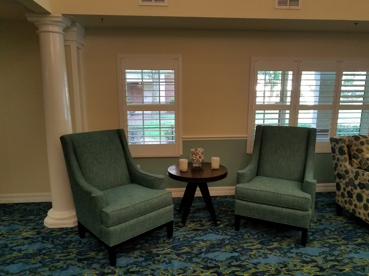 A cozy seating area with two armchairs and a small table in front of windows.