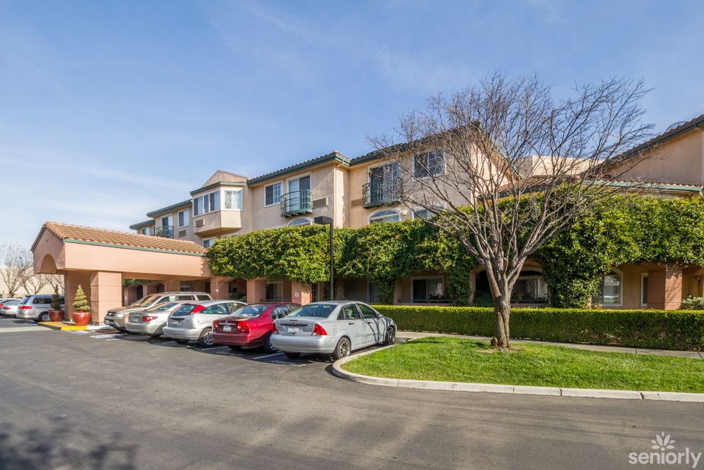 A sunny day view of a building with cars parked in the driveway.