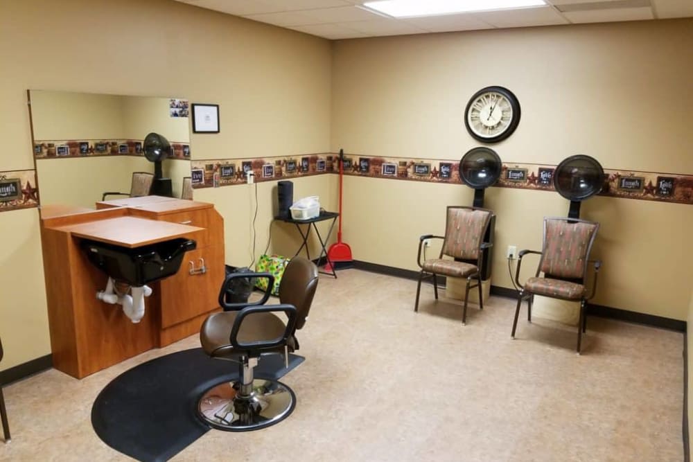 Interior of a hair salon with chairs, mirror, and hair dryers.