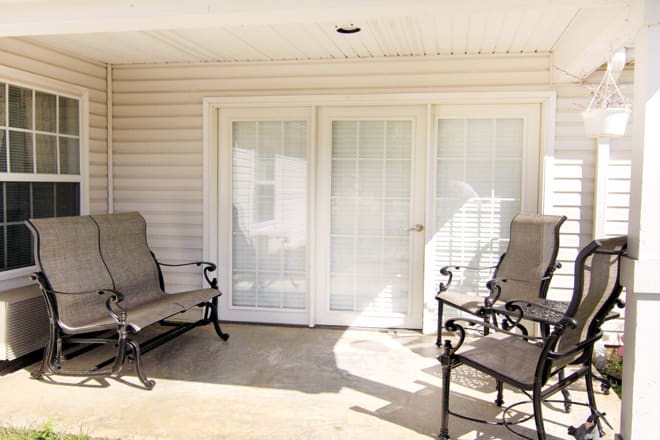 A cozy patio area with outdoor chairs and French doors, basking in the sunlight.