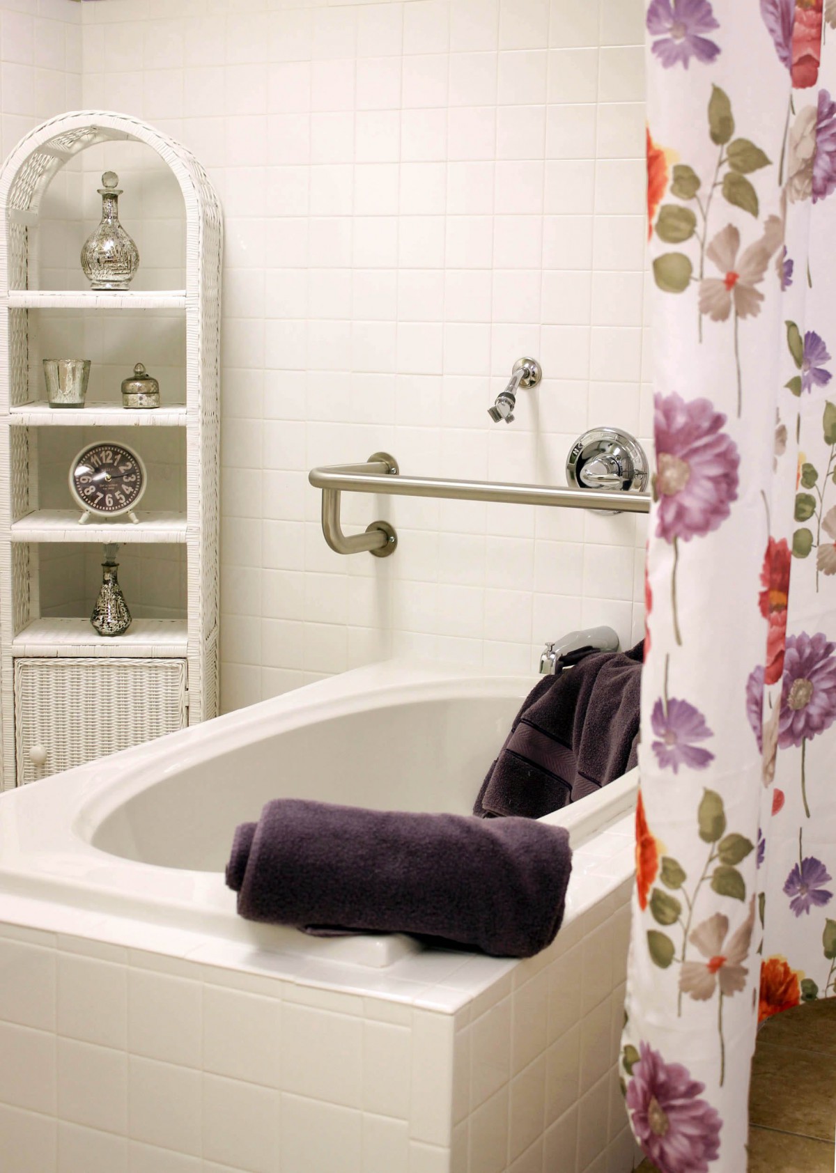 A bathroom featuring a bathtub with a floral shower curtain and neatly arranged towels.