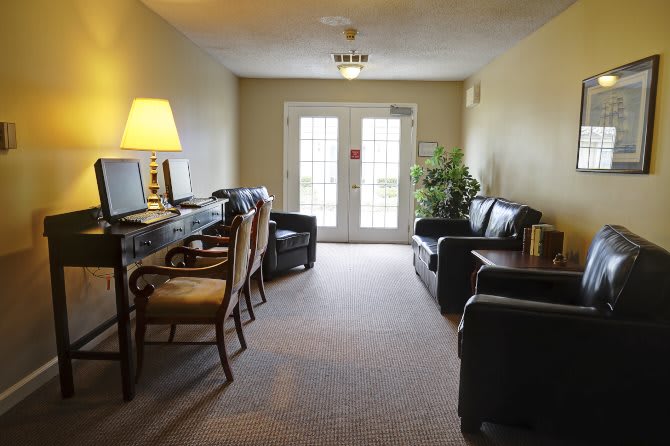 A cozy living room space with a computer desk, chairs, sofas, and a lamp.