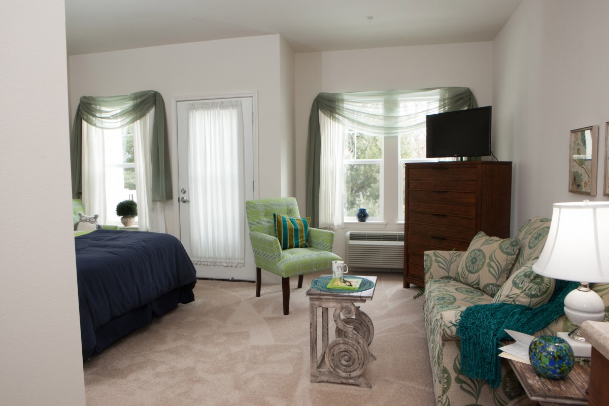 A cozy bedroom with a bed, seating area, and television.