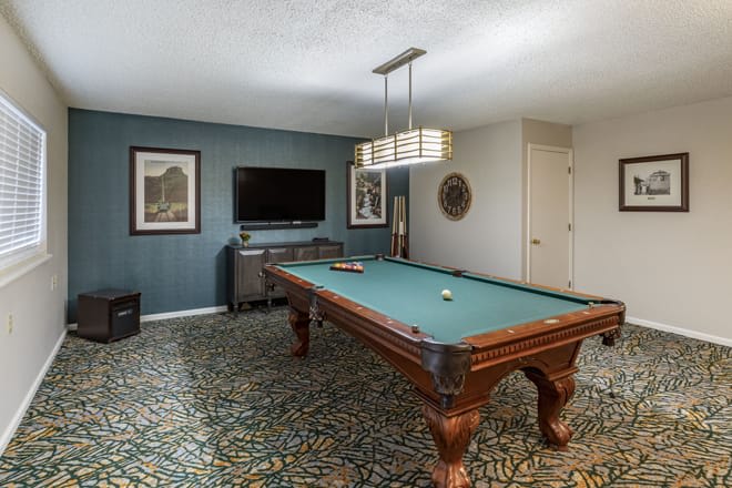A stylish game room featuring a pool table with modern decor and a carpeted floor.