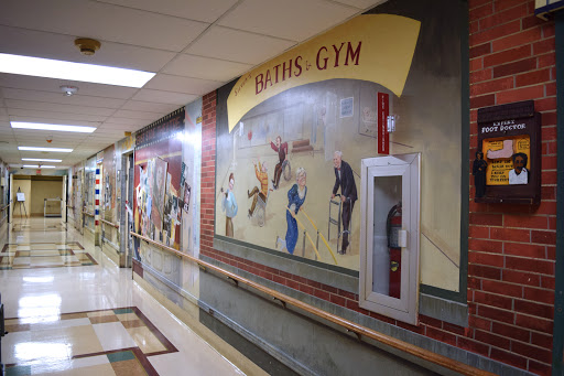 A vibrant mural depicting various sports activities in a gym hallway.