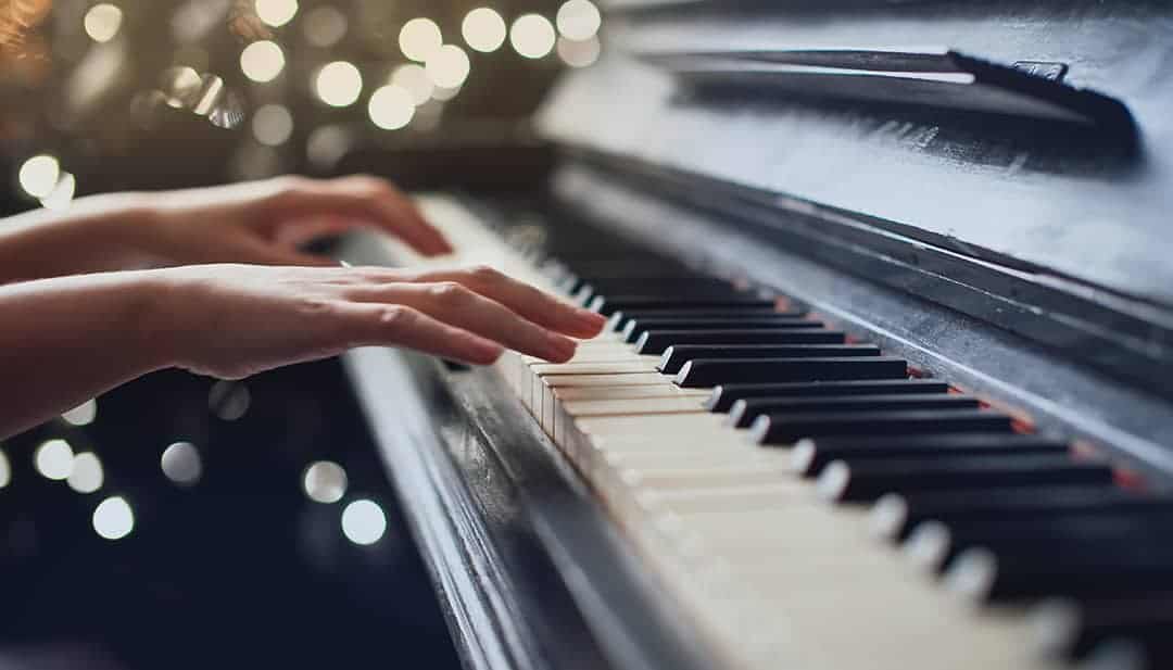 A person playing the piano with soft lighting in the background.