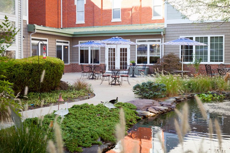 A serene garden patio with outdoor seating and a small pond surrounded by lush greenery.