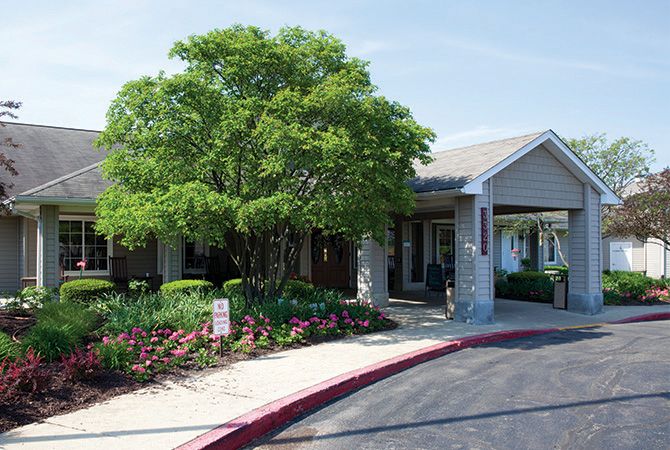 A building entrance surrounded by trees and a landscaped garden.