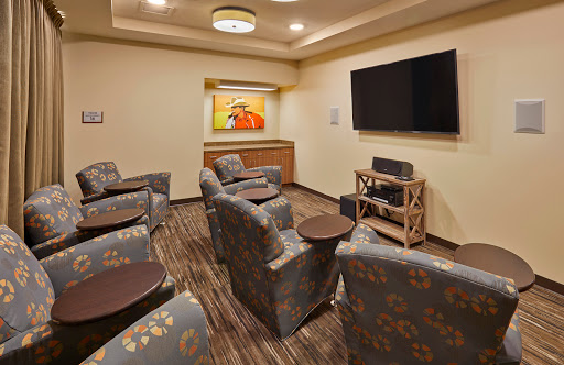 A cozy lounge area featuring comfortable chairs, a television for entertainment, and vibrant artwork on the walls.