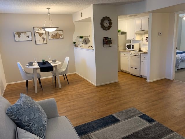 A cozy apartment with an open floor plan, featuring a living room, dining area, and kitchen with modern decor.
