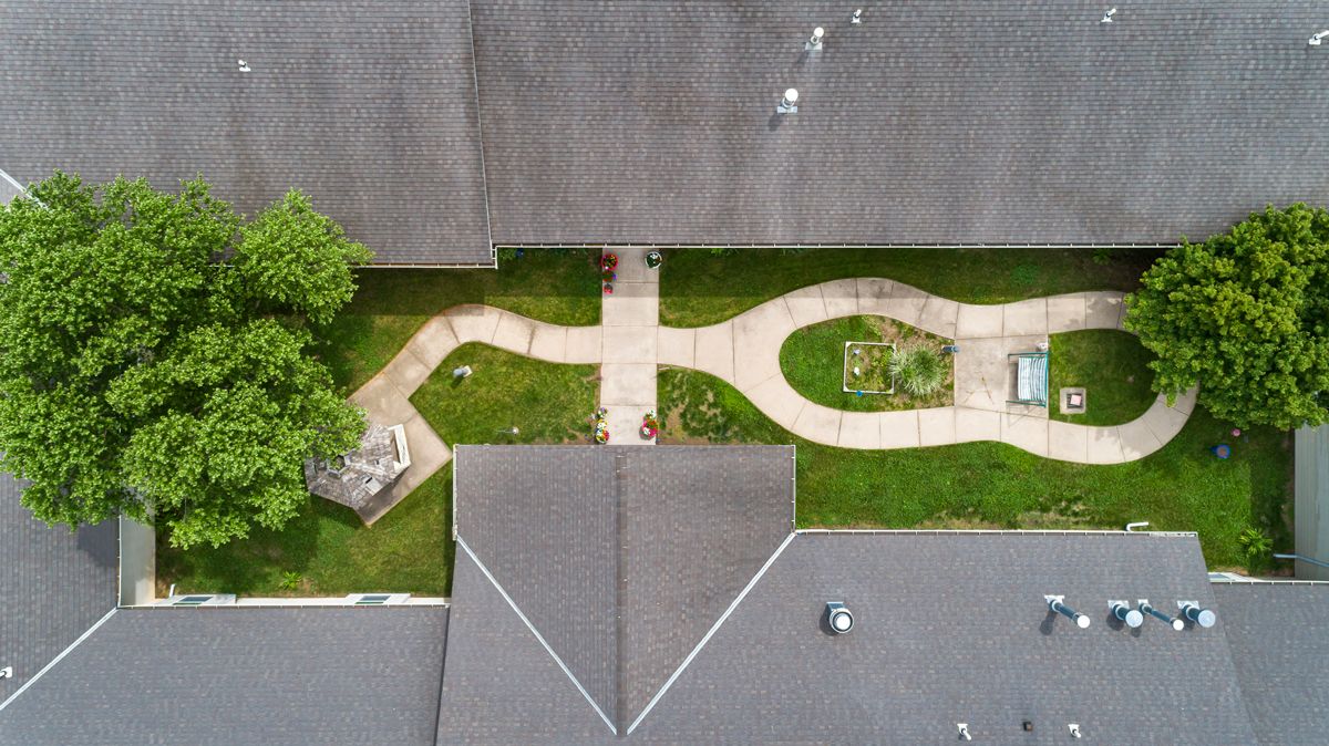An aerial view of a landscaped area with winding pathways between rooftops.