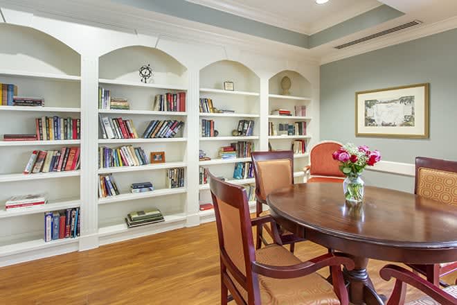 A cozy library interior with bookshelves and a dining table arrangement.