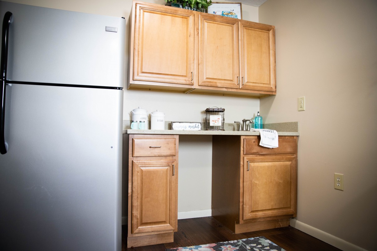 A compact kitchen area with wooden cabinets, a sink, and a refrigerator.