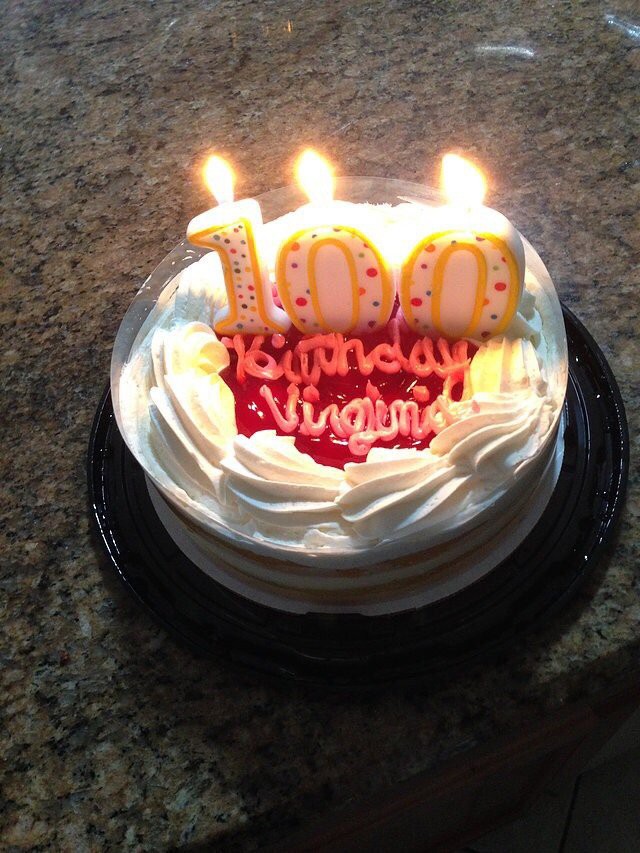 Birthday cake with '100' candles and icing decoration.
