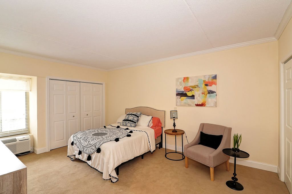 A cozy bedroom with a single bed, modern artwork, and a comfortable chair.