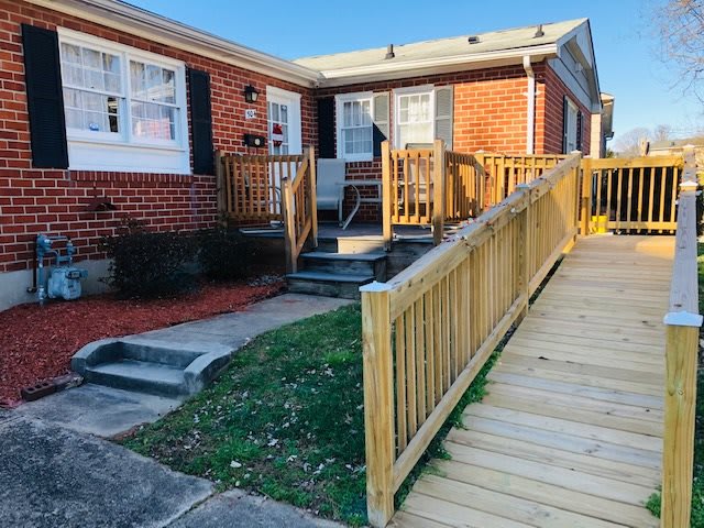 A brick house with a wooden accessibility ramp leading to the front entrance.