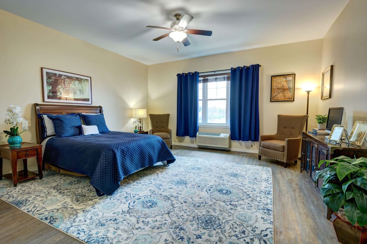 A well-decorated bedroom featuring a blue color scheme with stylish furnishings and a cozy atmosphere.