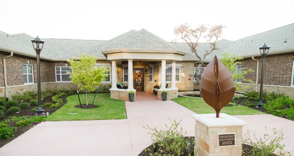Elegant building entrance with a garden and sculpture.