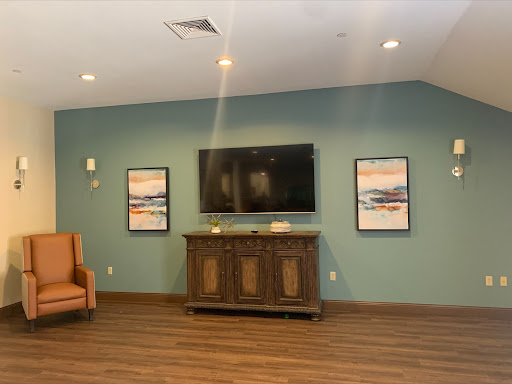 A cozy living room setup featuring a television, decorative art pieces, and wooden flooring.