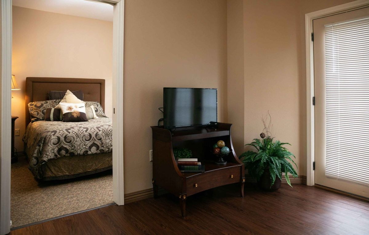 A cozy living space with a television and furniture, featuring a doorway leading to a bedroom.