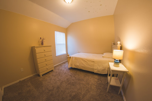 A cozy and inviting bedroom featuring a bed, a bedside table with a lamp, and a dresser against the wall.
