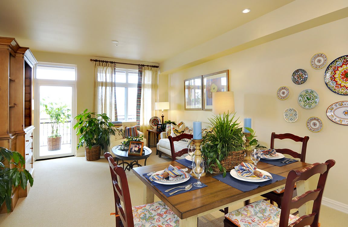 A cozy dining and living area with elegant table settings, greenery, and ample natural light.