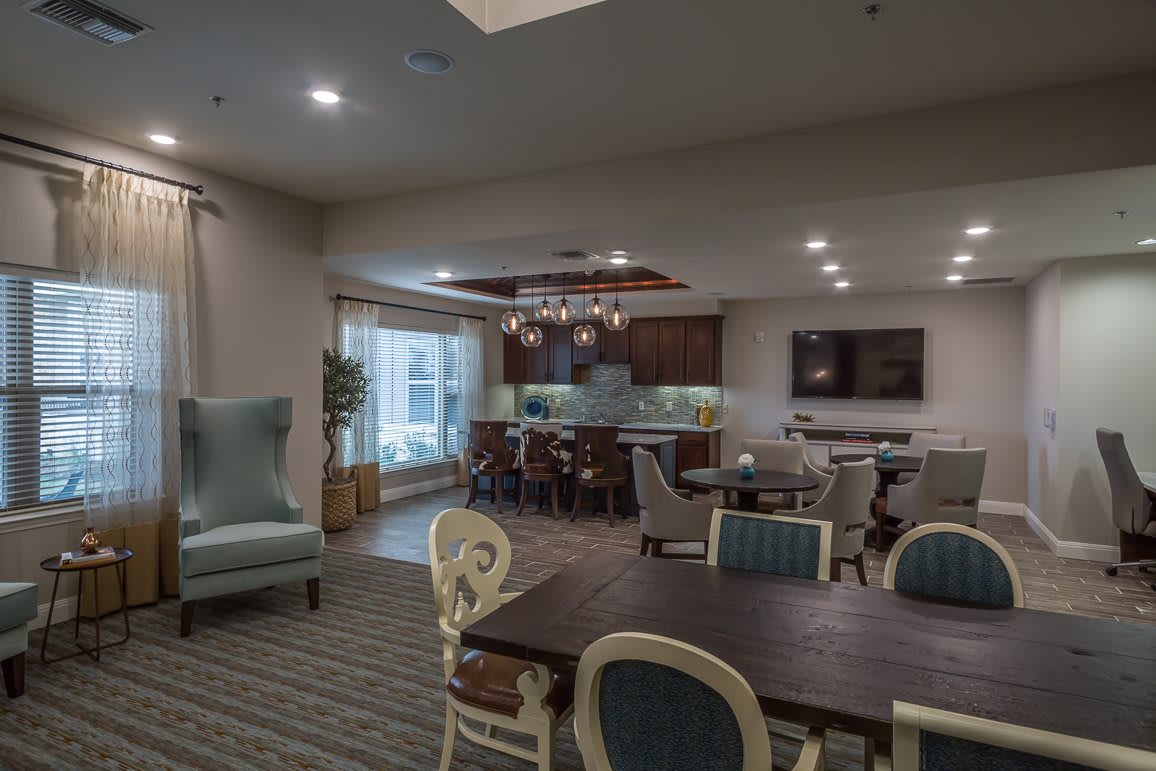 A cozy lounge area with a kitchen, dining tables, and a television.