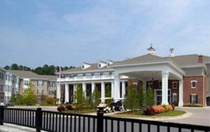A building with a grand entrance featuring columns and a landscaped foreground.