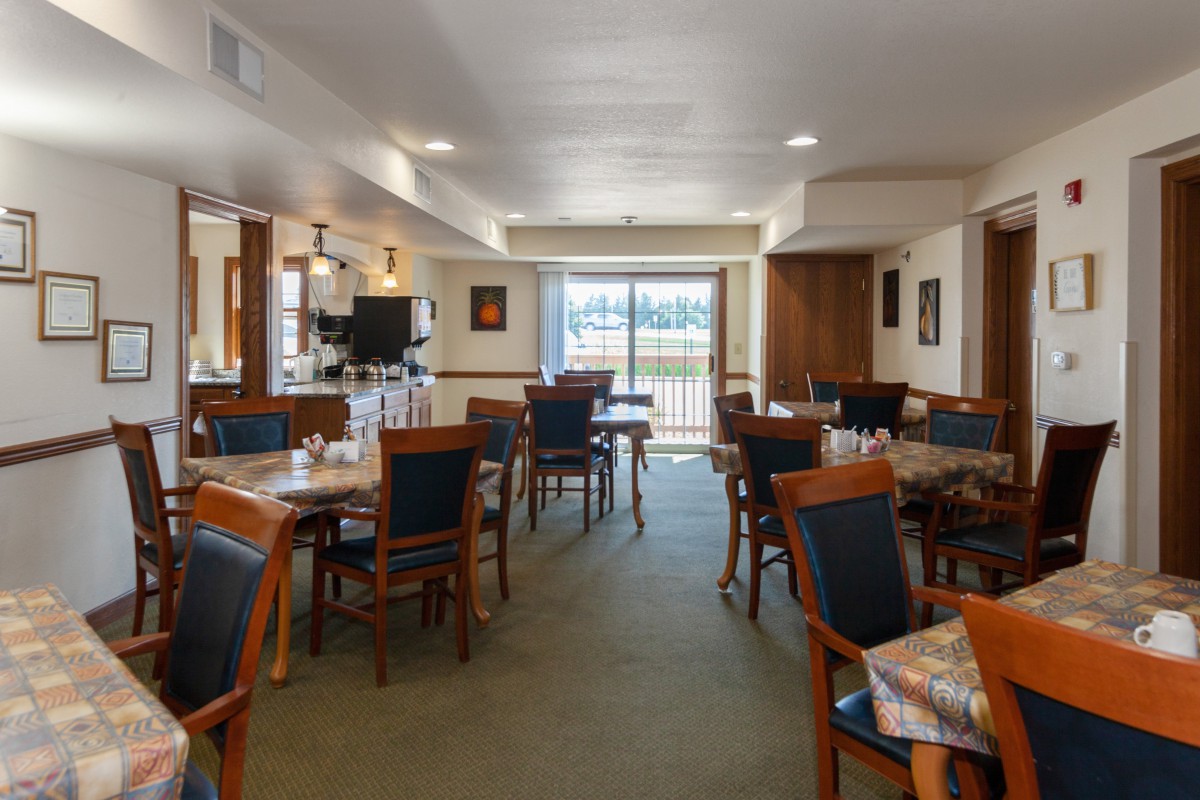 Spacious dining area with neatly arranged tables and chairs, featuring large windows for natural light.