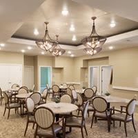 An elegantly designed dining area with round tables and chairs, highlighted by ornate chandeliers.