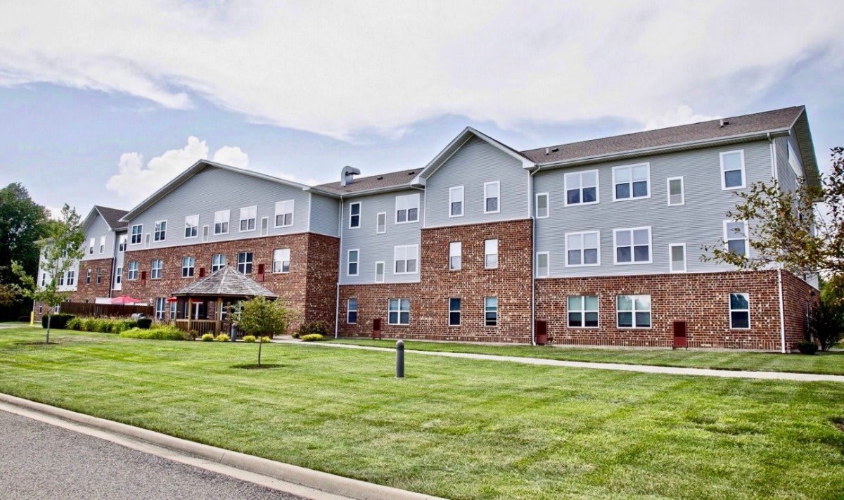 A modern apartment complex with a well-maintained lawn and brick facade.