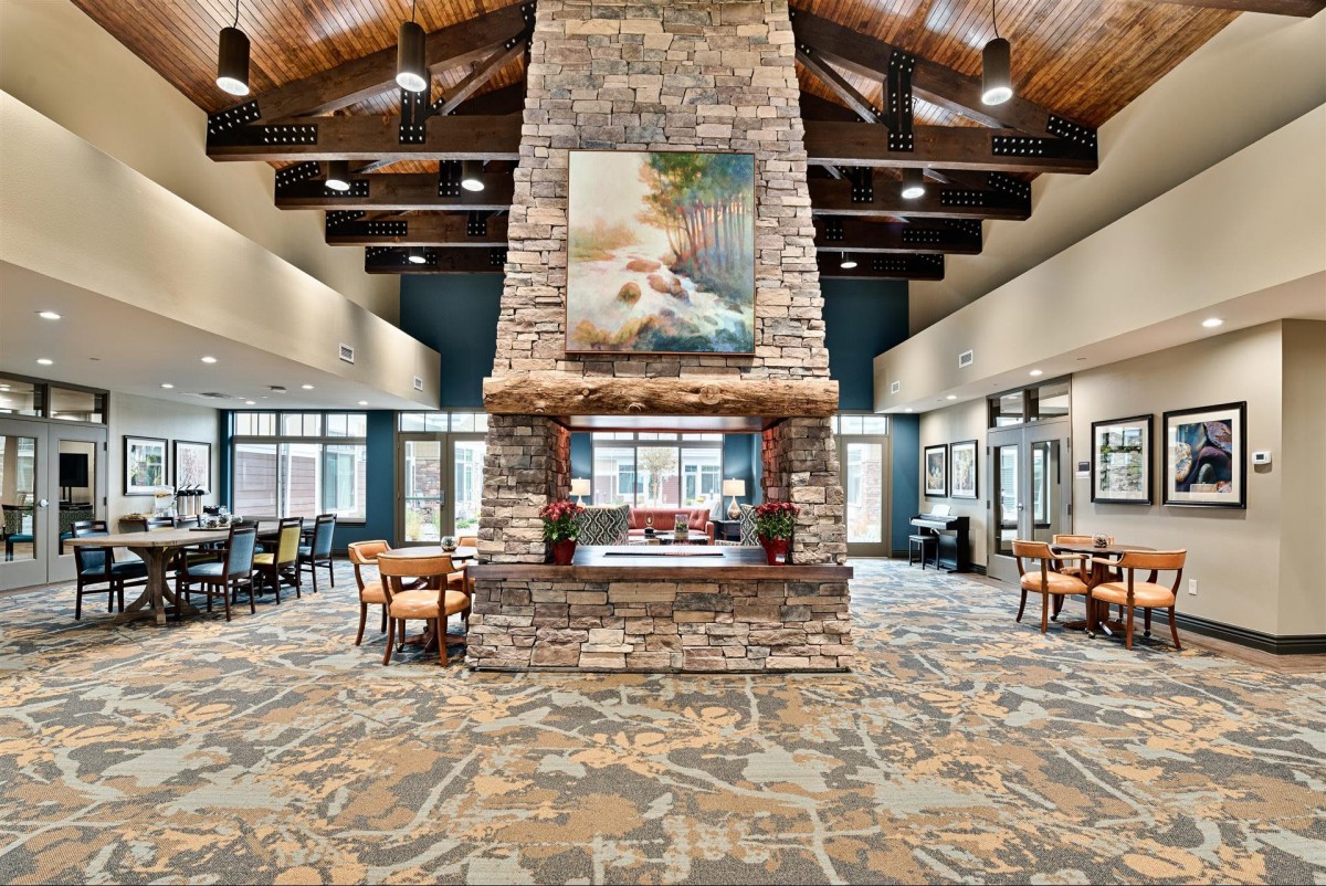 A modern lobby with a central stone fireplace and comfortable seating areas.