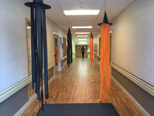 A hallway decorated for Halloween with orange and black hanging witch hats.