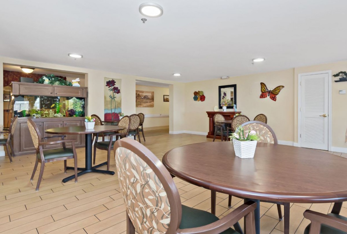 A cozy indoor dining area with tables, chairs, a fish tank, and decorative artwork on the walls.