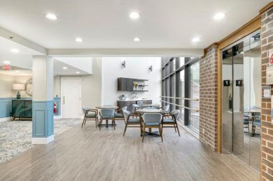 A modern dining area with wooden flooring and large windows.