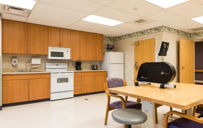 A kitchen area featuring wooden cabinets, a stove, refrigerator, and seating.